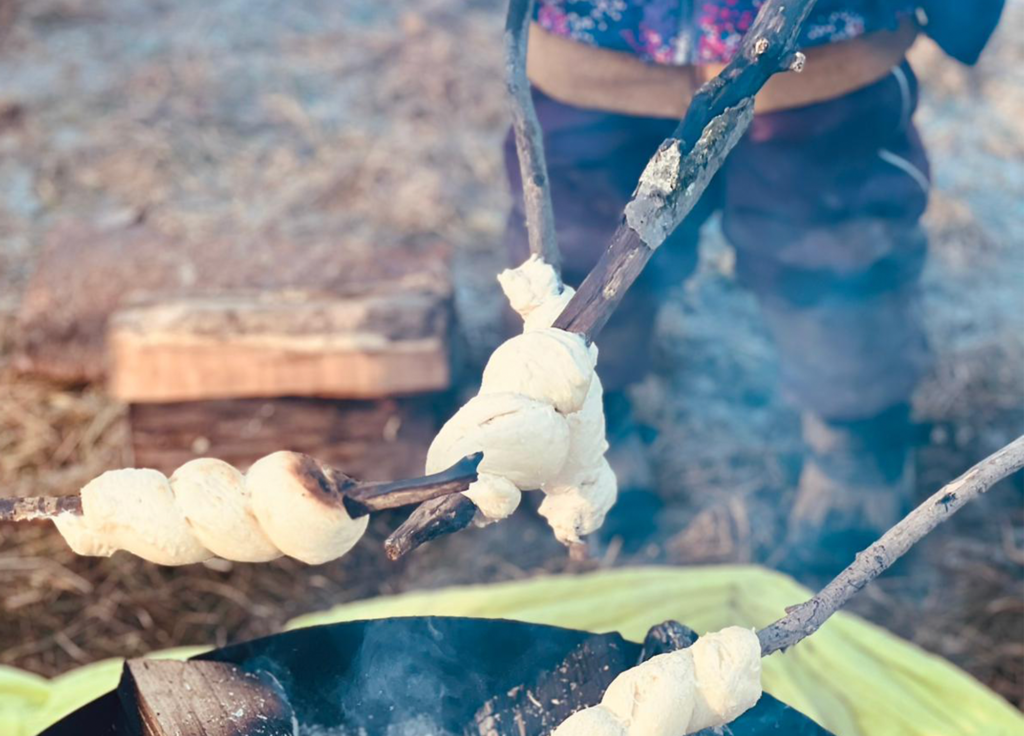 Kinder backen Stockbrot am Lagerfeuer
